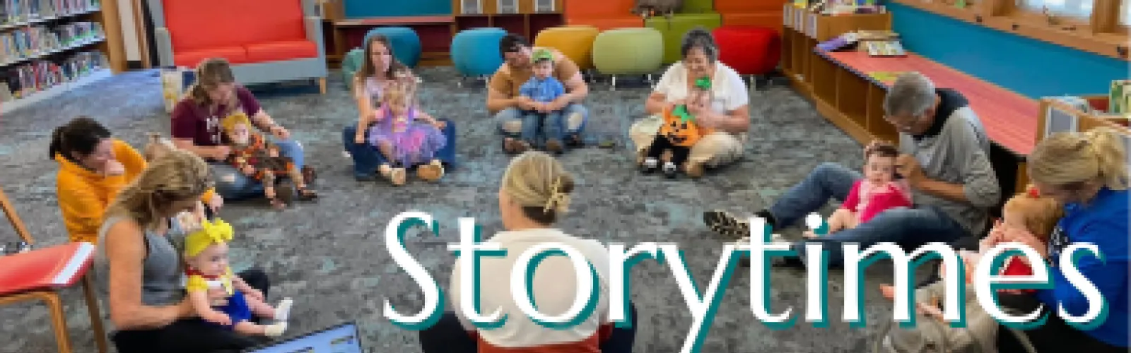 Children sitting on the floor looking at an adult reading a book; Click for information about story times.